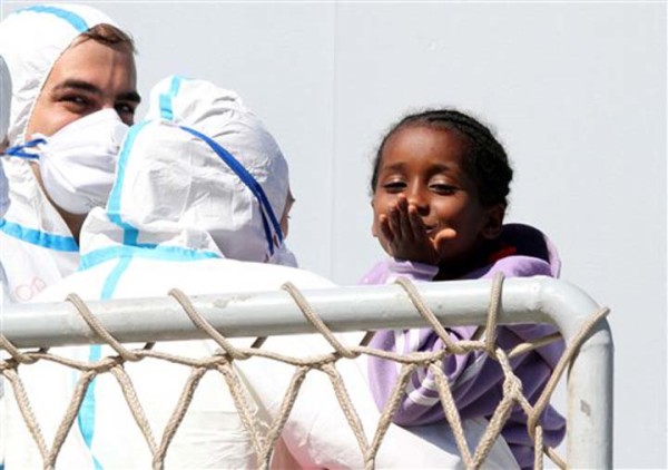 A child blows a kiss as migrants disembark from the Italian Navy frigate Bersagliere at the Reggio Calabria harbor, Italy, Monday, May 4, 2015. Italy's Coast Guard and Navy as well as tugs and other commercial vessels joined forces to rescue migrants in at least 16 boats Sunday, saving hundreds of them and recovering 10 bodies off Libya's coast, as smugglers took advantage of calm seas to send packed vessels across the Mediterranean. Sunday's drama at sea came a day after 3,690 migrants were saved from smugglers' boats. Most of those migrants are still being taken to southern Italian ports even as the fresh rescues were taking place. (AP Photo/Adriana Sapone)