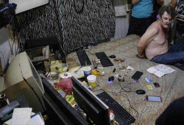 In this April 20, 2017, photo, suspected child webcam cybersex operator, David Timothy Deakin, from Peoria, Ill., with his hands tied behind his back during a raid by investigators, sits on his bed where he handles online sharing of videos of children engaging in sexual acts in Mabalacat, Philippines. (AP)